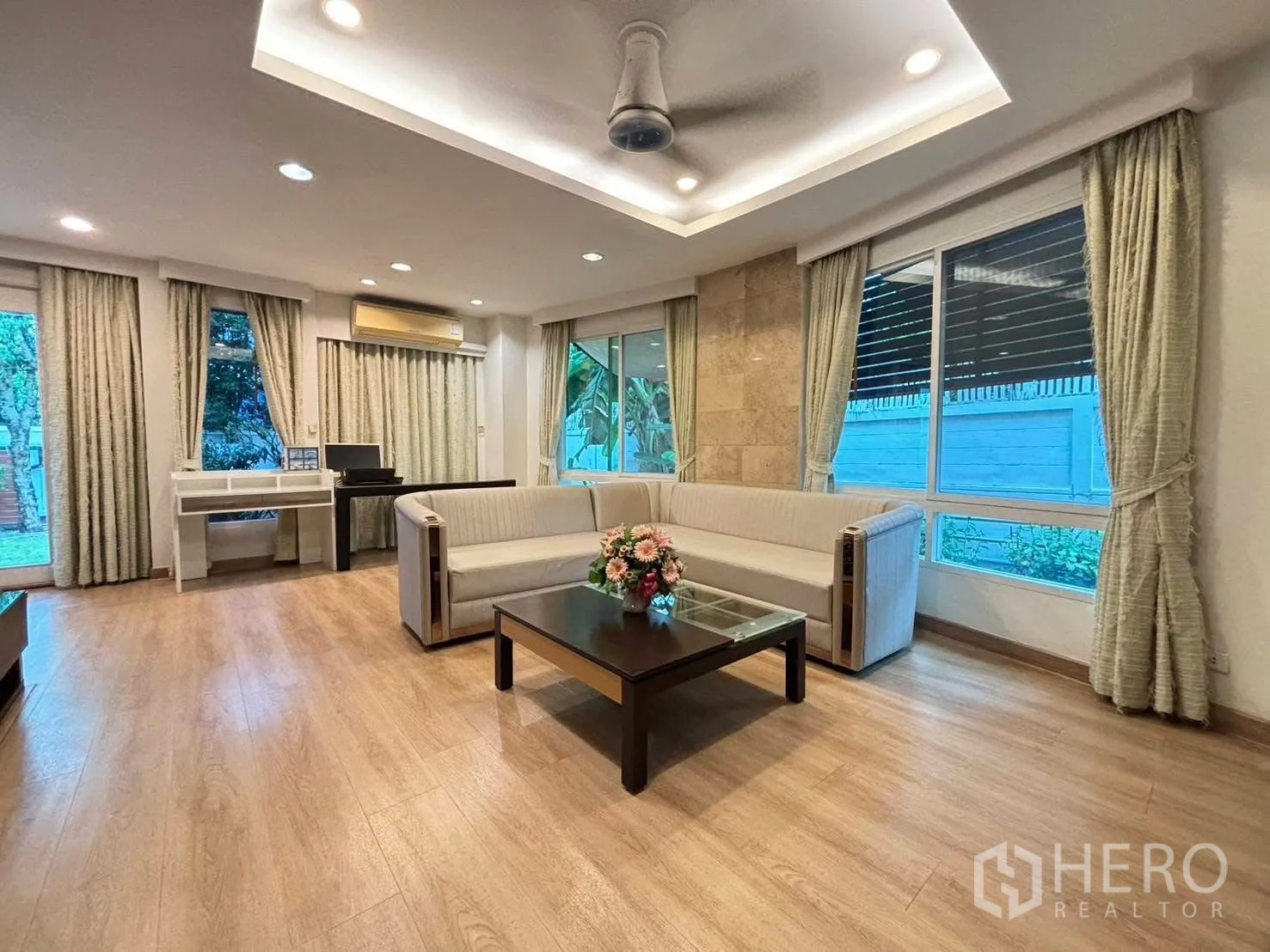 Detached House for rent in Bang Kapi, Bangkok - Bright living room with L-shaped sofa, wood floors and large windows.
