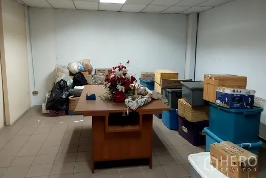 Factory for sale in Bang Phli, Samut Prakan - Storage room with a table and stacks of plastic bins and boxes.