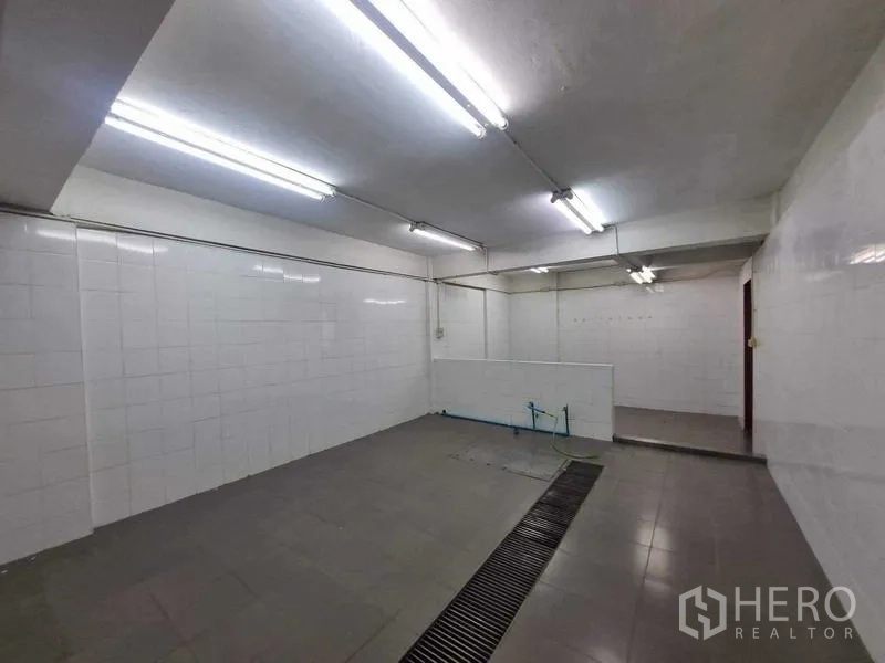 Retail Space for rent in Bang Rak, Bangkok - Large tiled utility area with floor drain channel, bright fluorescent lights and a partial divider wall.