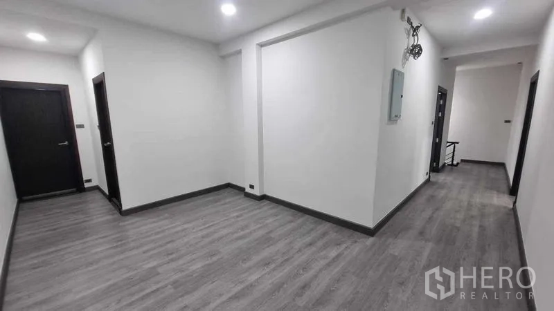 Townhouse for rent in Khlong Toei, Bangkok - Bright hallway with gray wood-look flooring and recessed lights inside the townhouse.