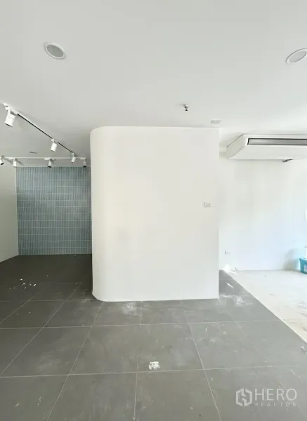 Retail Space for rent - Curved feature wall with grey tiles and a blue tile accent backdrop under track lights.