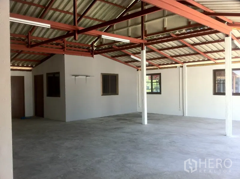 Warehouse for rent in Lam Luk Ka, Pathum Thani - Warehouse interior featuring a built-in office room with windows beneath a metal roof frame.