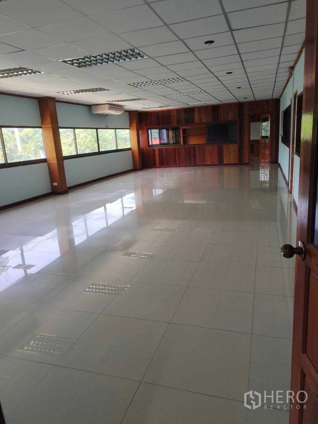 Factory for sale in Nikhom Phatthana, Rayong - Open-plan office with large windows, glossy tiles and a wood feature wall.