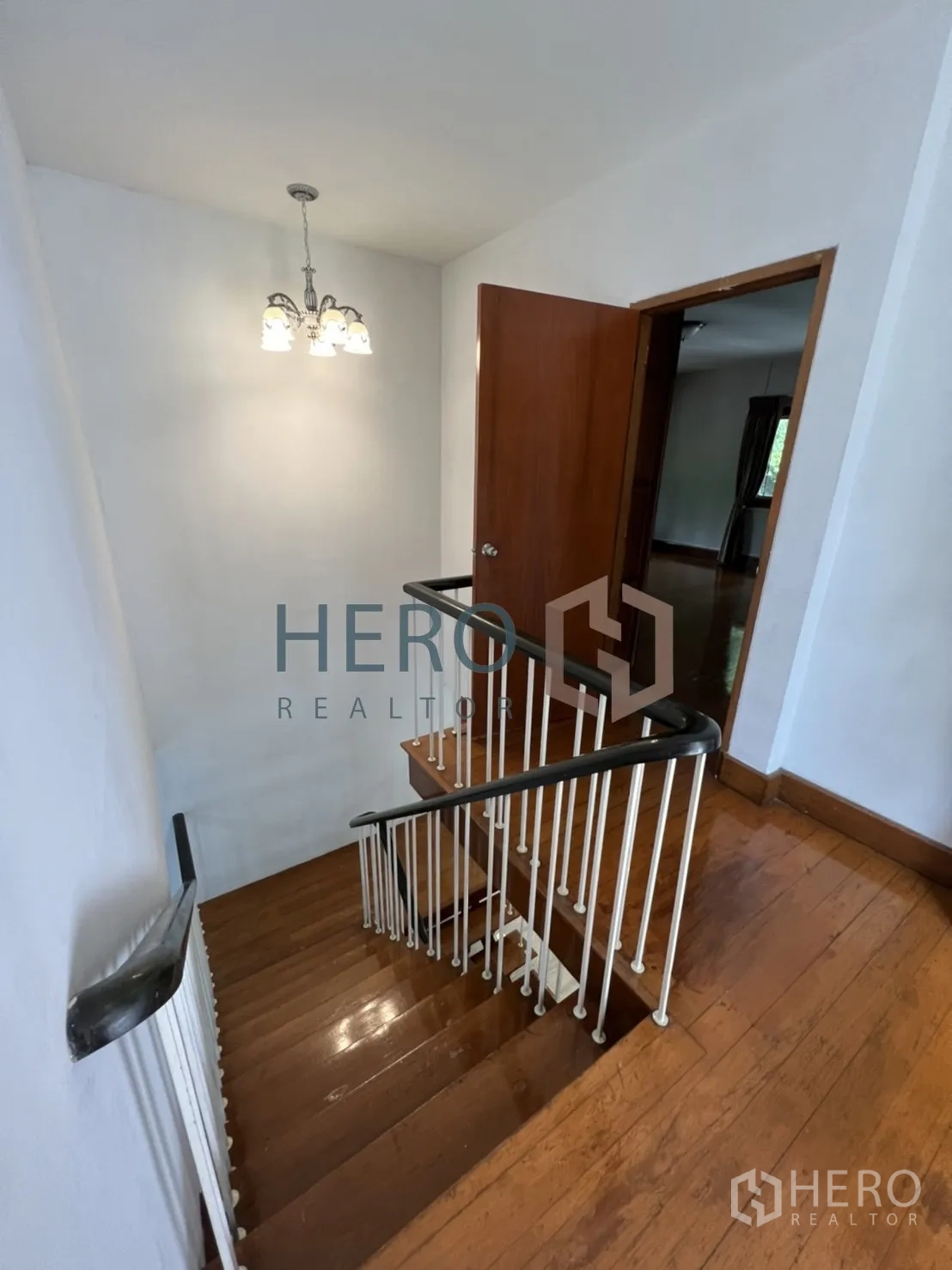 Detached House for rent in Watthana, Bangkok - Staircase with wooden steps, white balusters and a hanging light.