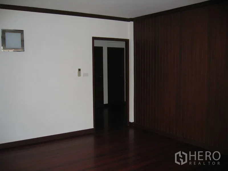Detached House for rent in Watthana, Bangkok - Room with dark timber wall panels and doorway to corridor.