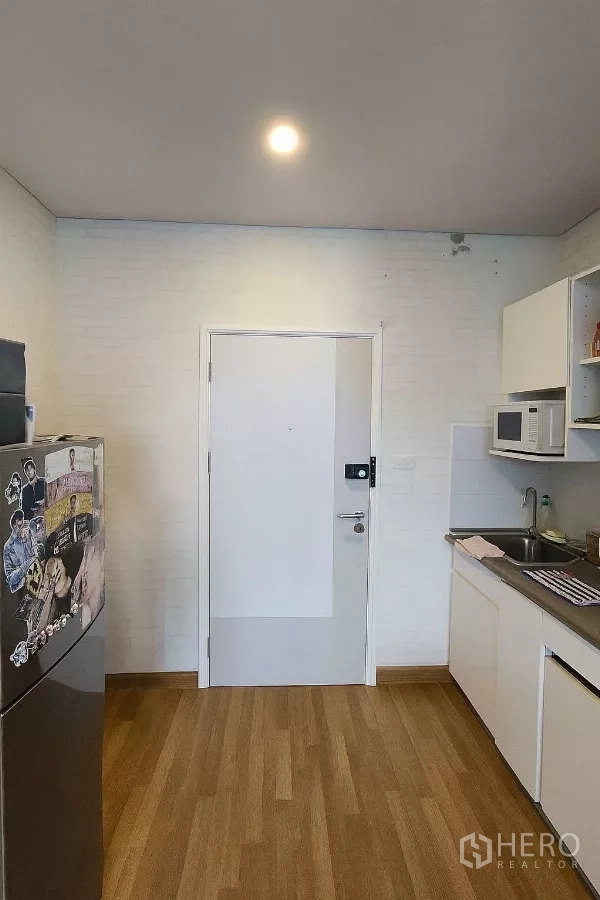 Detached House for sale - Compact kitchen with white cabinets, stainless countertop, sink, microwave, and fridge.