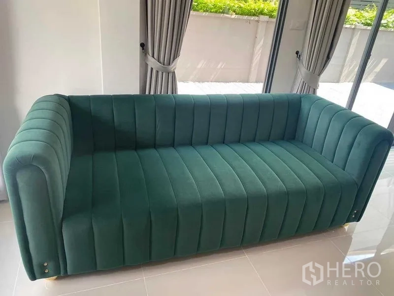 Detached House for rent in Khan Na Yao, Bangkok - Living area featuring a green velvet sofa beside floor‑to‑ceiling sliding doors.