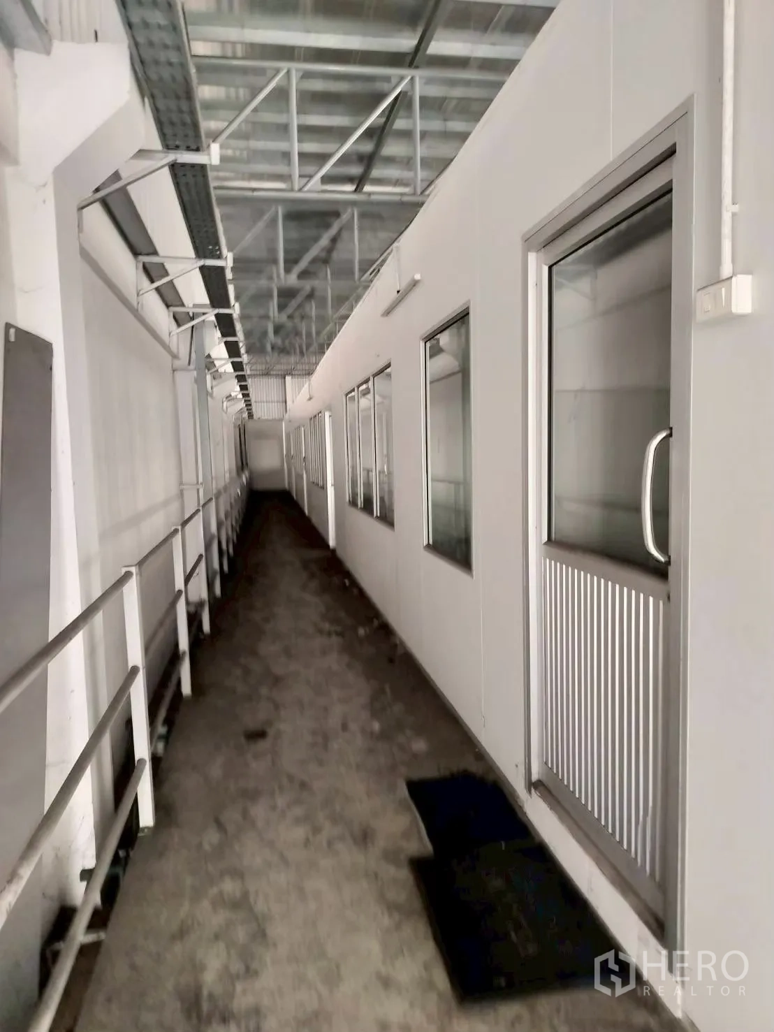 工厂 for sale in Bang Phli, Samut Prakan - 工业走廊，带金属扶手、白色夹芯板墙、窗口与玻璃门，顶部为钢结构屋顶。