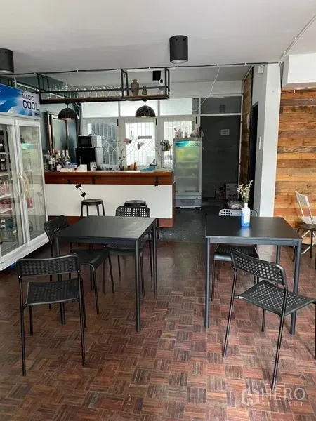 Home Office for rent in Pathum Wan, Bangkok - Cafe-style bar with hanging lights, glassware rack and black dining tables in front.