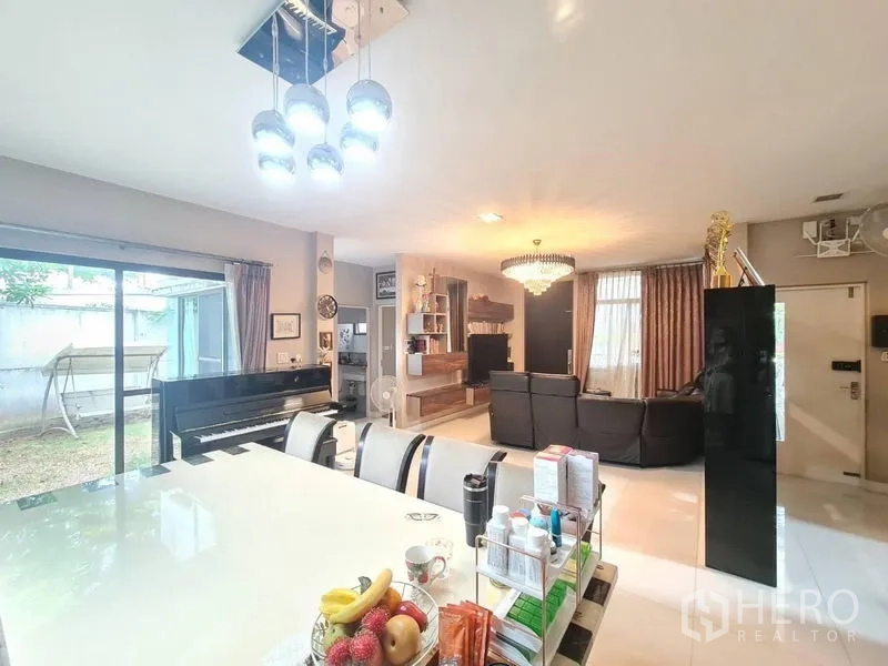 Detached House for sale in Prawet, Bangkok - Open‑plan dining and living space with piano and sliding doors to the garden.