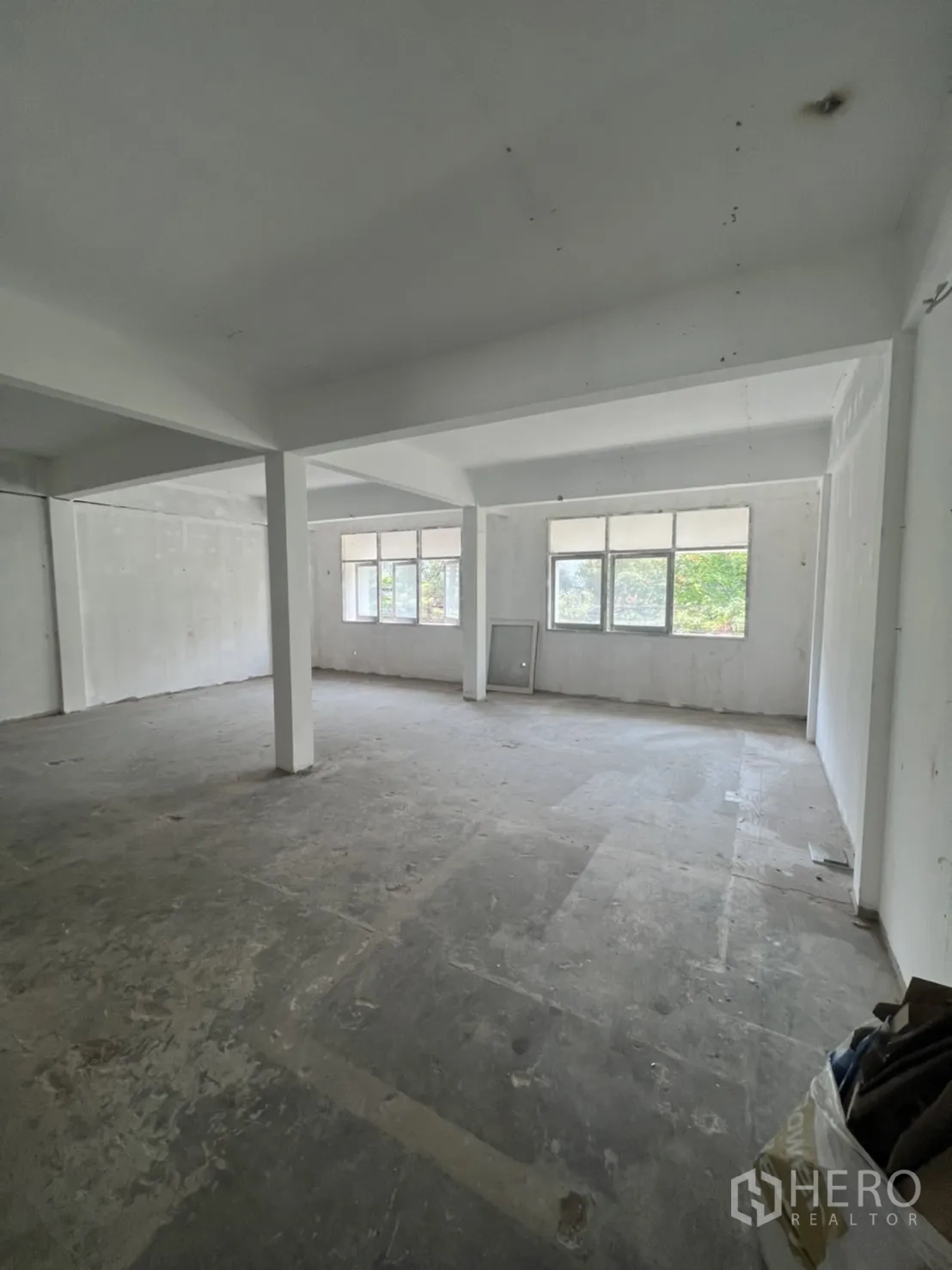 Shophouse for rent in Watthana, Bangkok - Open-plan upper floor with support columns and wide windows providing natural light.