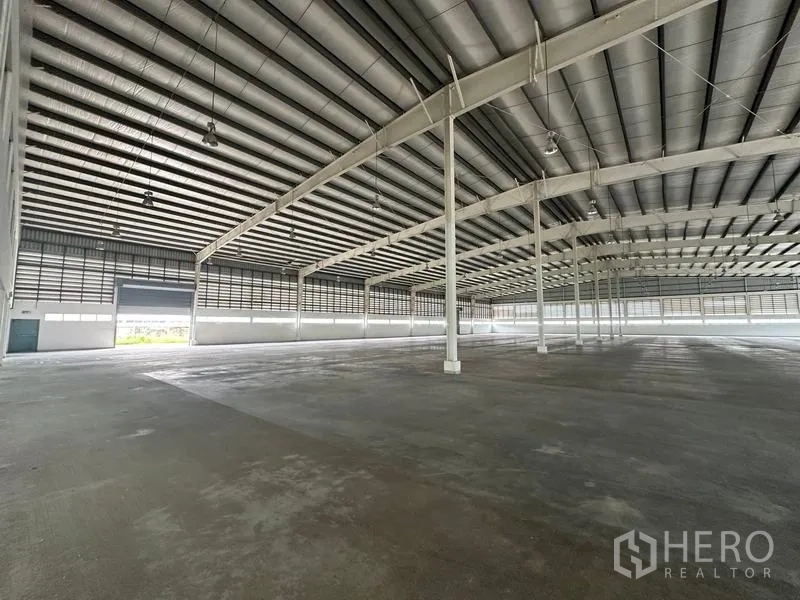 Factory for rent in Pathum Thani - Factory interior showing roller shutter door and wide-span columns.