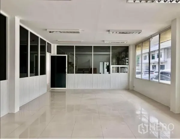Warehouse for rent in Prawet, Bangkok - Bright ground-floor office area with large windows and fluorescent lighting.