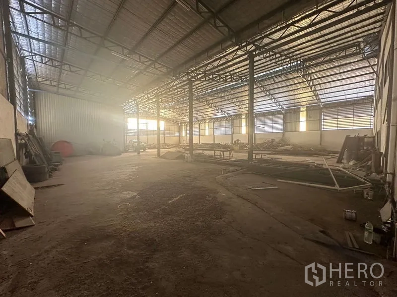 Warehouse for rent in Saphan Sung, Bangkok - Wide warehouse interior with metal roof, ventilation panels and support columns.