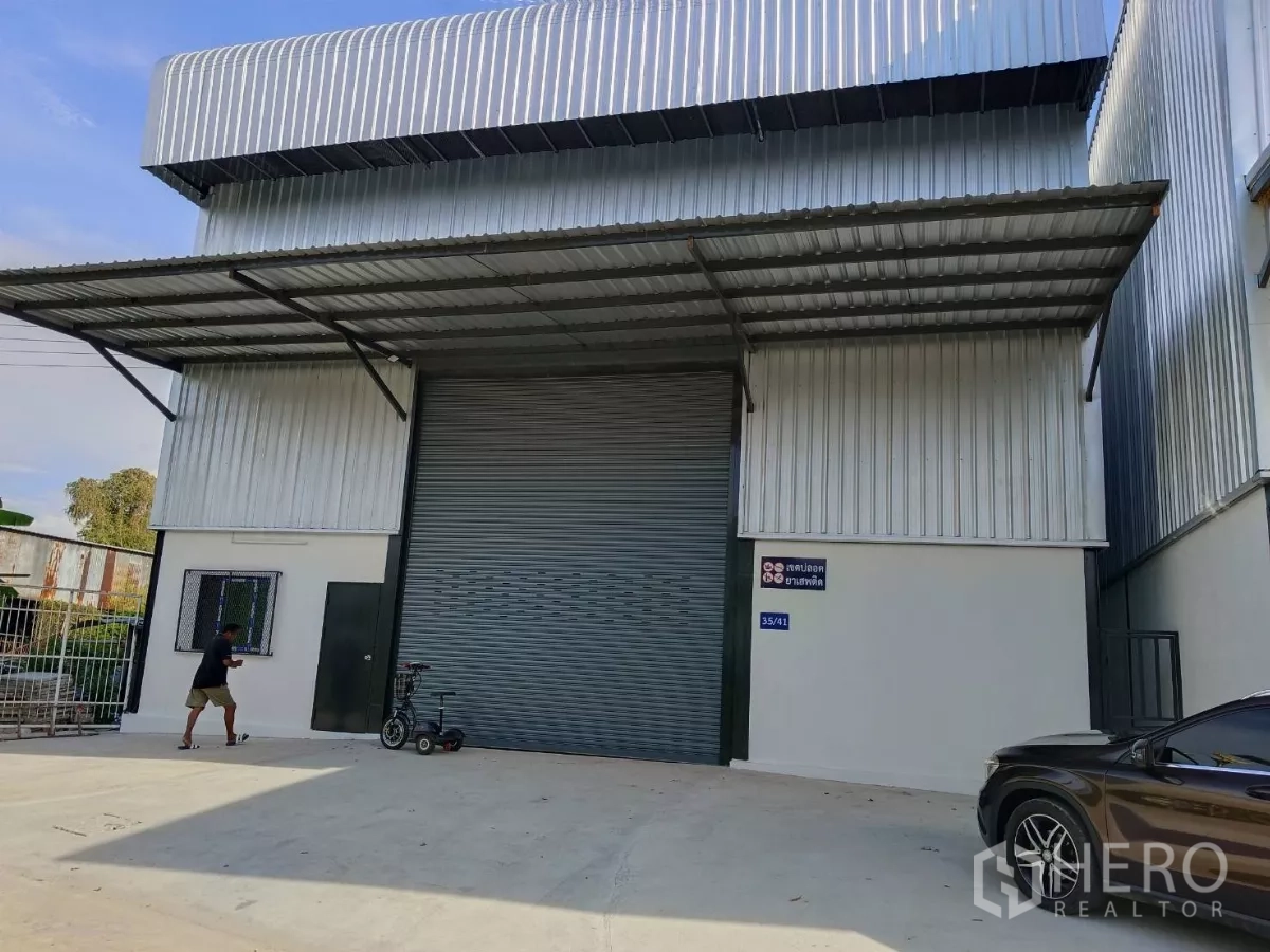 货栈 出租在Bang Phli, Samut Prakan - 仓库正立面，超宽卷帘门与装卸前坪及侧窗。