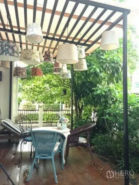 Detached House for rent or sale in Prawet, Bangkok - Covered patio with pergola, hanging lamps and garden seating in a detached house.