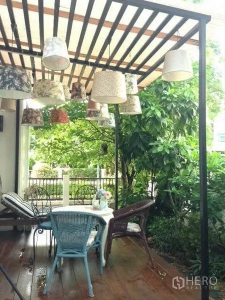 Detached House for rent or sale in Prawet, Bangkok - Covered patio with pergola, hanging lamps and garden seating in a detached house.