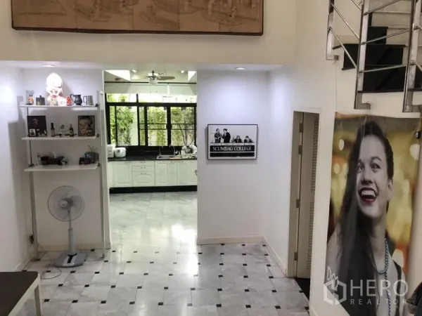 Townhouse for rent or sale in Bangkok - Open hallway with marble floors leading to the kitchen, built-in shelving and a metal stair rail.