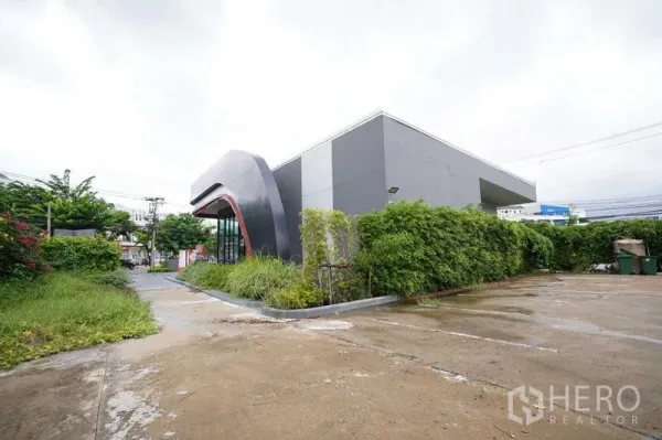Standalone for rent in Bang Na, Bangkok - Modern standalone commercial building with curved facade, wide driveway and parking.