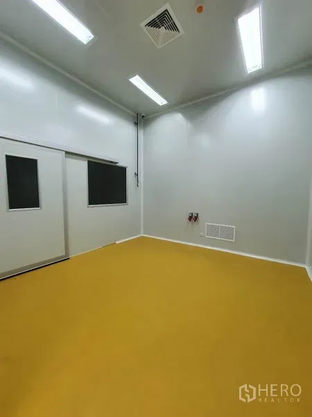 Factory for sale in Lam Luk Ka, Pathum Thani - Clean production room with white walls, yellow epoxy floor, ceiling lights and ventilation.