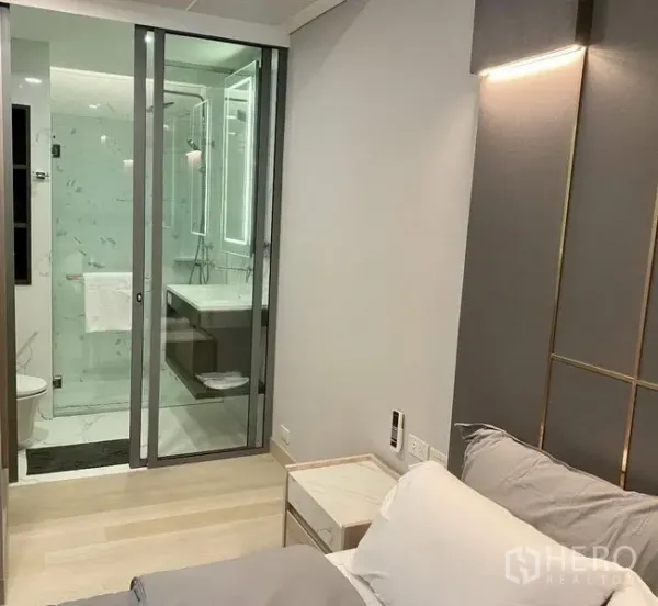 公寓 出租在Khlong Toei, Bangkok - 卧室通向玻璃隔断卫浴，带背光镜与浅色木地板。