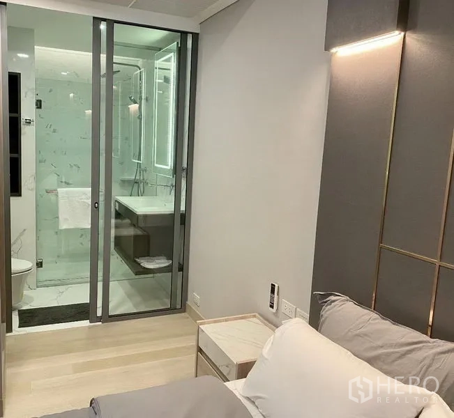公寓 出租在Khlong Toei, Bangkok - 卧室通向玻璃隔断卫浴，带背光镜与浅色木地板。