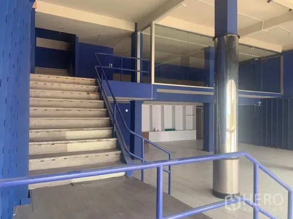 Shophouse for rent in Watthana, Bangkok - Open-plan shophouse interior with a wide staircase, mezzanine glass room, and polished column.