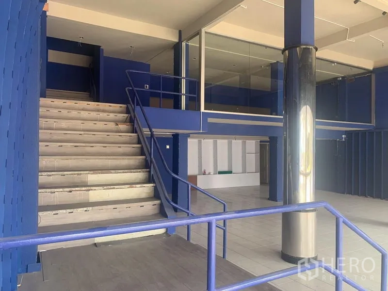 Shophouse for rent in Watthana, Bangkok - Open-plan shophouse interior with a wide staircase, mezzanine glass room, and polished column.