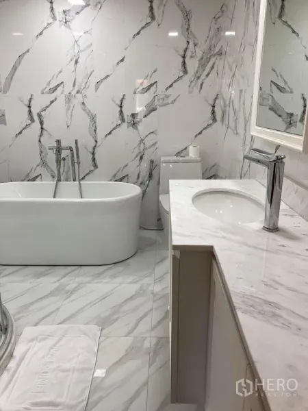 Detached House for rent in Khlong Toei, Bangkok - Modern bathroom with marble tiles, freestanding bathtub and vanity