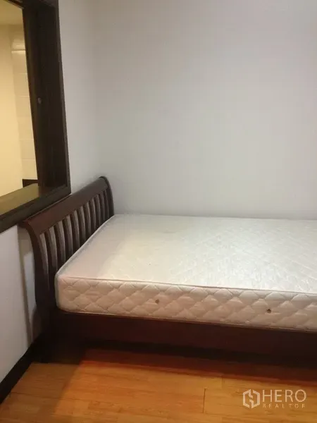 Condominium for rent in Pathum Wan, Bangkok - Cozy second bedroom with single bed beside interior window and wood floor.