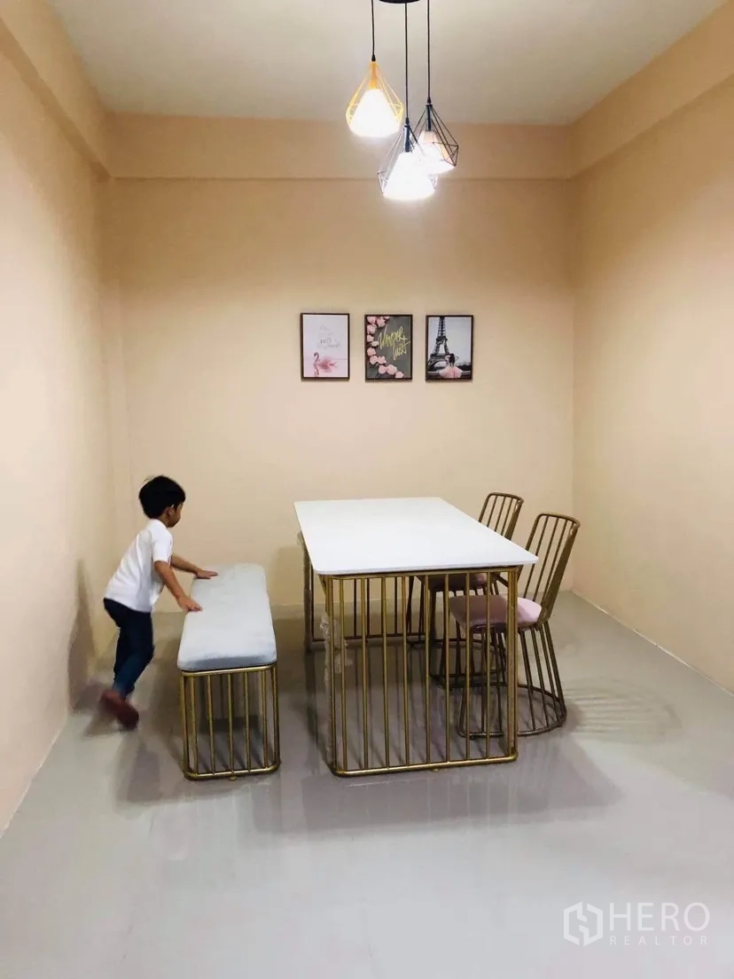 Townhouse for rent or sale in Huai Khwang, Bangkok - Built-in kitchen with grey counters, white cabinets and blue range hood, next to a bathroom.