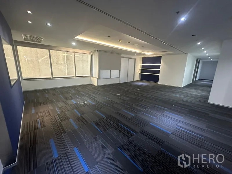 Office Space for rent in Khlong Toei, Bangkok - Open office zone with a blue accent wall, recessed lighting, and carpet tiles.