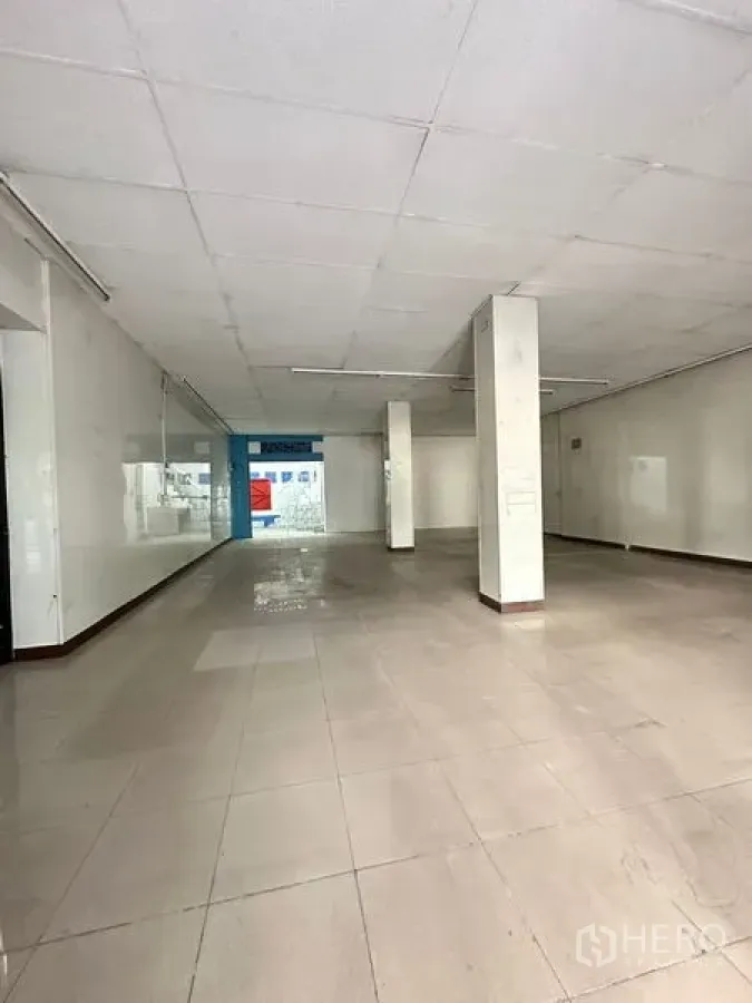 Shophouse for rent in Bang Na, Bangkok - Ground-floor shophouse interior with tiled floors, white walls and support columns.