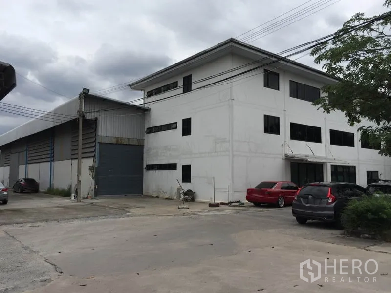 Warehouse for rent in Saphan Sung, Bangkok - Exterior view of warehouse and three-storey office building with roller shutter loading door and on-site parking.