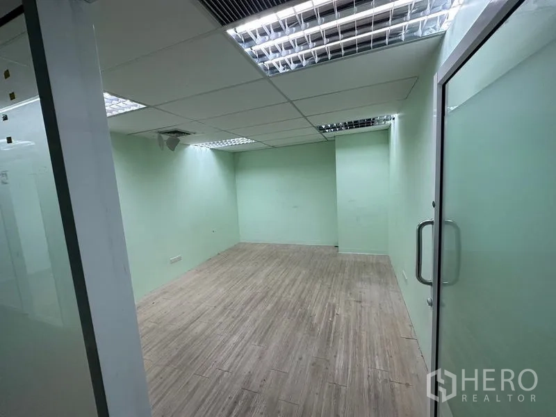 办公空间 出租 - 封闭会议室，磨砂玻璃门、浅绿色墙面与嵌入式荧光灯。