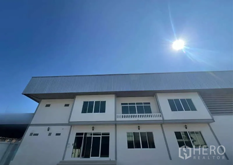 Warehouse for rent in Prawet, Bangkok - Modern two-storey warehouse facade with metal roof under a clear blue sky.