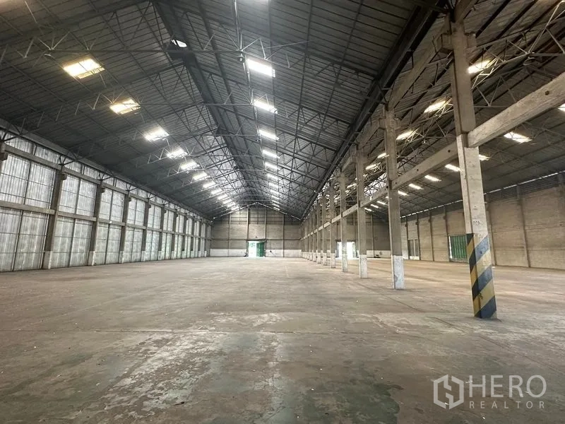Warehouse for rent in Mueang Pathum Thani, Pathum Thani - High‑clear roof with skylights and translucent side panels illuminating the warehouse space.