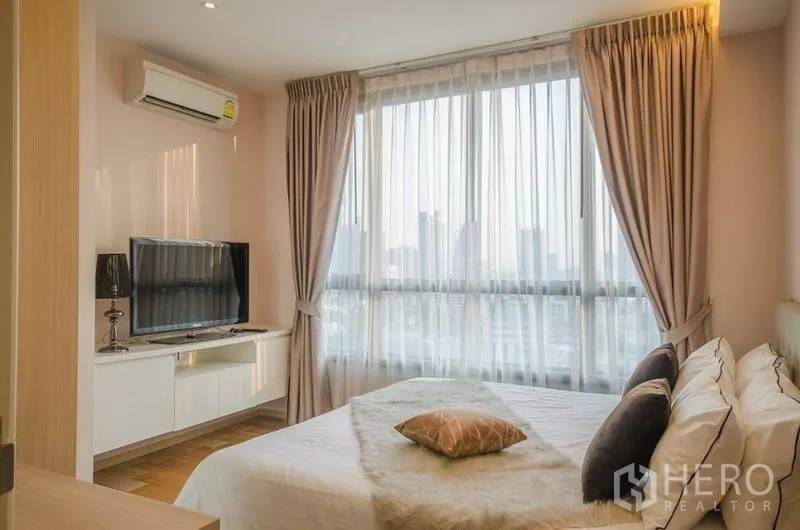 Condominium for rent or sale in Watthana, Bangkok - Master bedroom with TV console, air conditioner and full-height windows.