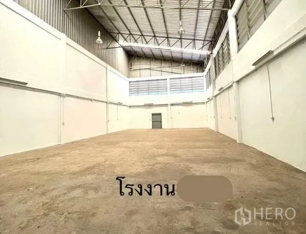 Factory for rent or sale in Mueang Samut Sakhon, Samut Sakhon - Spacious warehouse hall with high steel truss ceiling, white walls and concrete floor.