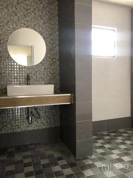 Factory for rent in Pak Kret, Nonthaburi - Modern washroom featuring mosaic accent wall, round mirror and vanity sink.