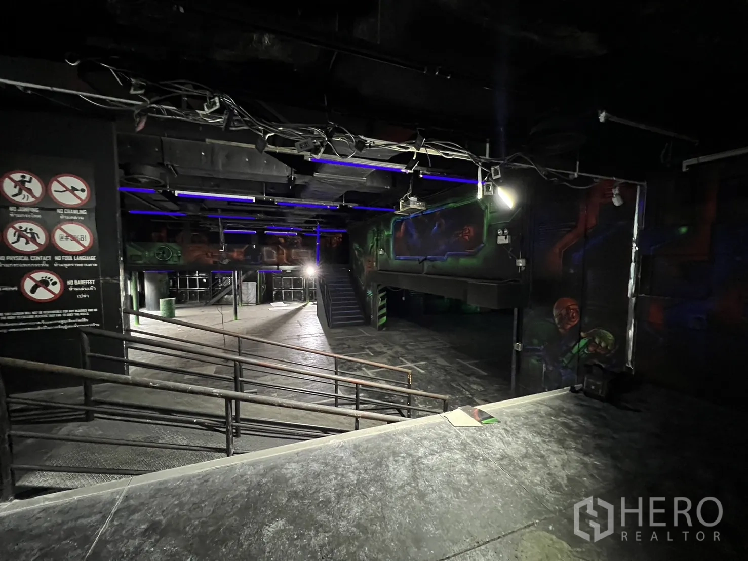 Retail Space for rent in Khlong Toei, Bangkok - Open-plan space with ramps, safety signage and mezzanine under a black ceiling.