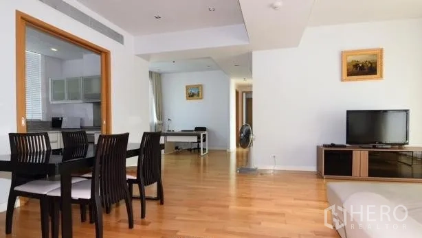 Condominium for rent in Khlong Toei, Bangkok - Open-plan living and dining area with wood floors, a dining set, TV console, and a compact home office nook.