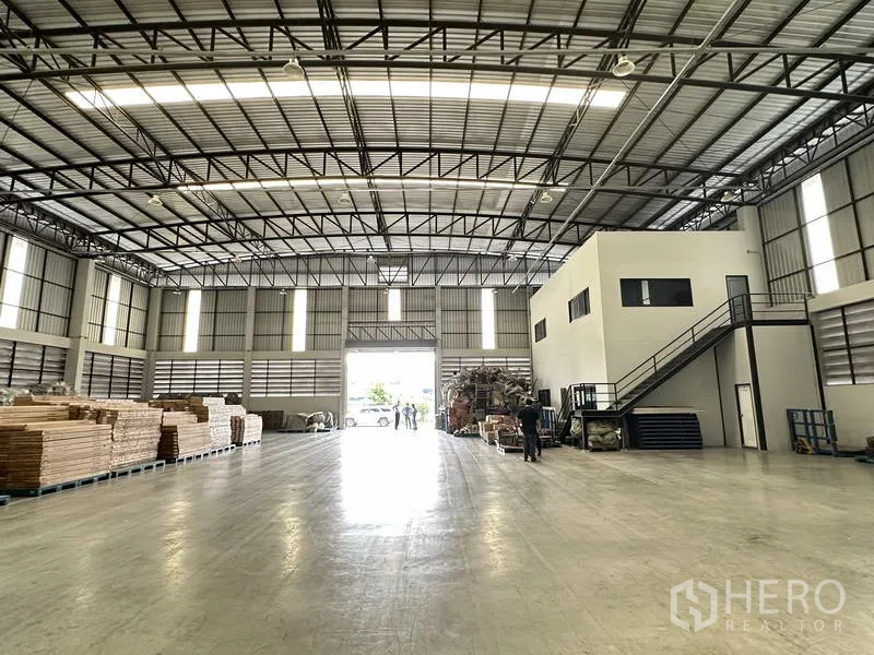 Warehouse for rent in Bang Phli, Samut Prakan - Bright warehouse interior facing a roller shutter entrance with ample storage area and an internal office cube.