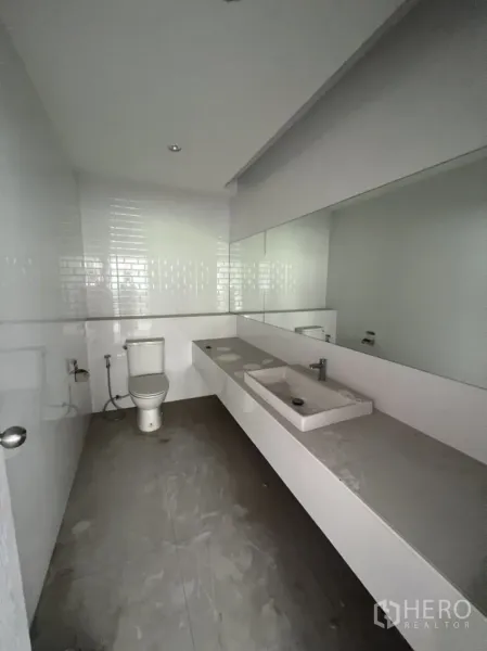 Shophouse for rent in Watthana, Bangkok - Clean restroom featuring a long countertop with sink, large mirror and toilet.
