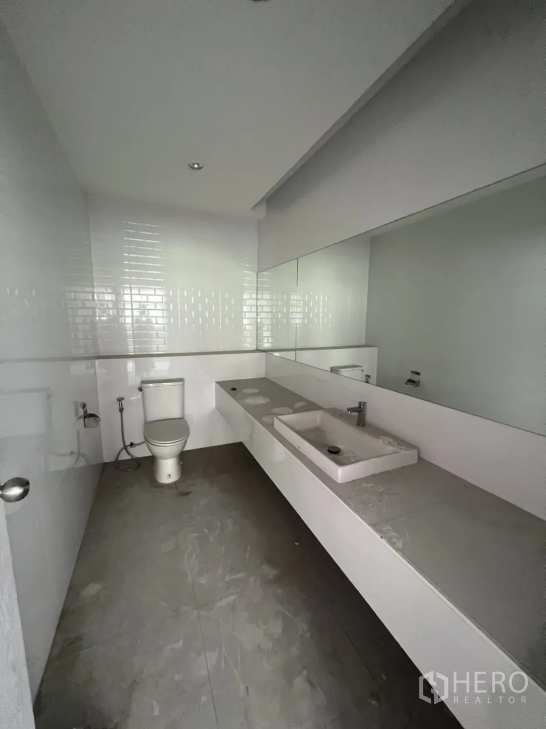 Shophouse for rent in Watthana, Bangkok - Clean restroom featuring a long countertop with sink, large mirror and toilet.