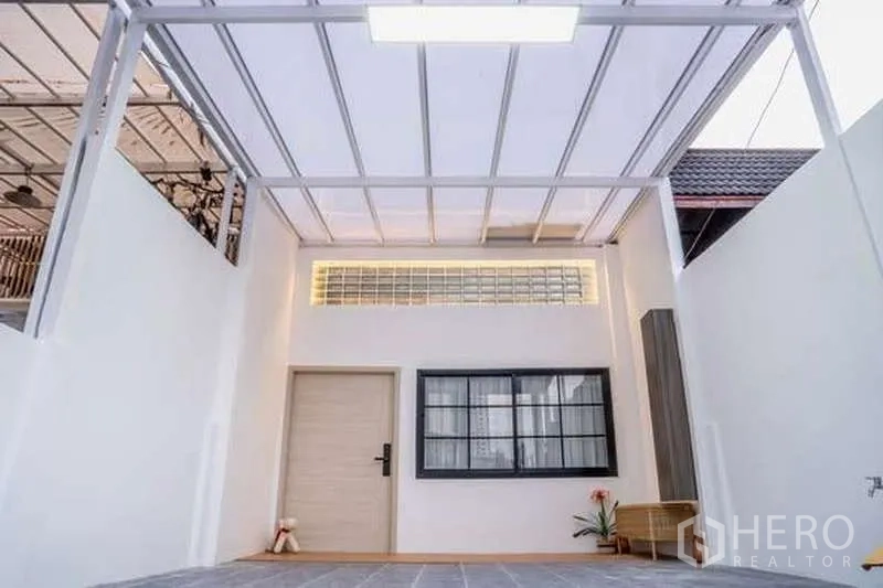 Townhouse for rent in Khlong Toei, Bangkok - Covered front carport with white metal roof, glass-block transom, window and entry door.