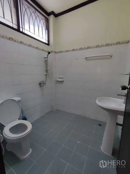 บ้าน ให้เช่าในKhlong Toei, Bangkok - ห้องน้ำปูกระเบื้อง พร้อมโถสุขภัณฑ์ ฝักบัว และอ่างล้างหน้า ใต้หน้าต่างสูง