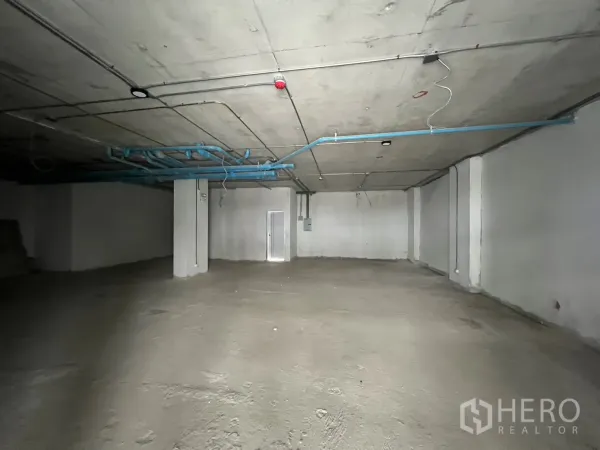 Retail Space for rent - Open-plan retail space with structural columns and visible piping ready for tenant fit-out.