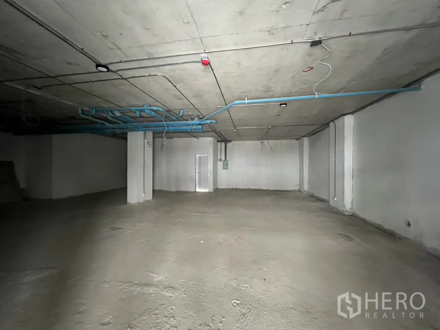 Retail Space for rent - Open-plan retail space with structural columns and visible piping ready for tenant fit-out.