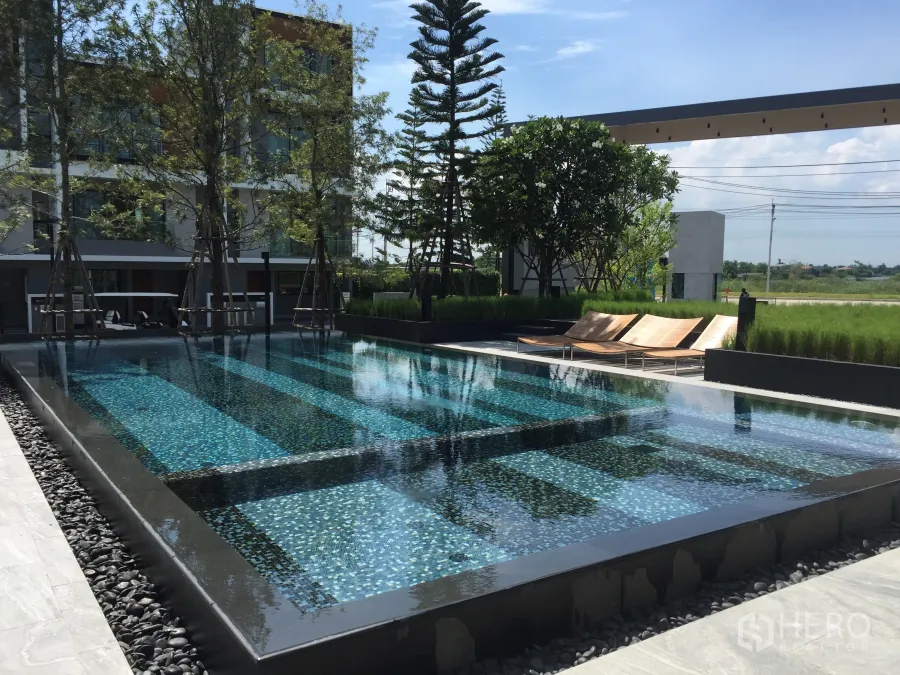 联排别墅 出租在Saphan Sung, Bangkok - 联排社区的现代公共泳池，设躺椅与景观花园。
